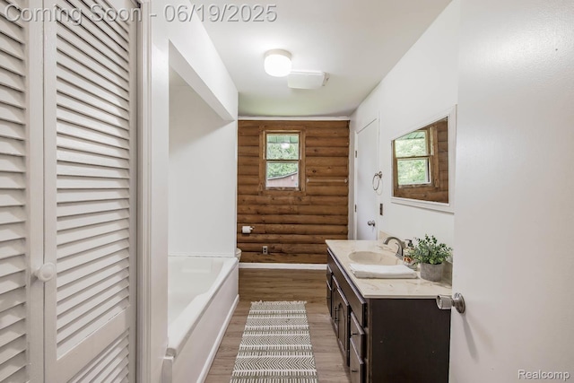 5180 Hillsboro Rd, Davisburg, MI 48350 - bathroom with rustic walls, vanity, wood finished floors, a garden tub, and a closet