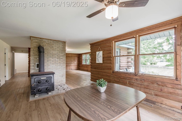 5180 Hillsboro Rd, Davisburg, MI 48350 - dining area featuring wood finished floors, log walls, a wood stove, and a ceiling fan