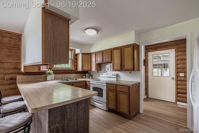 5180 Hillsboro Rd, Davisburg, MI 48350 - kitchen with electric range, rustic walls, a peninsula, a kitchen bar, and brown cabinetry