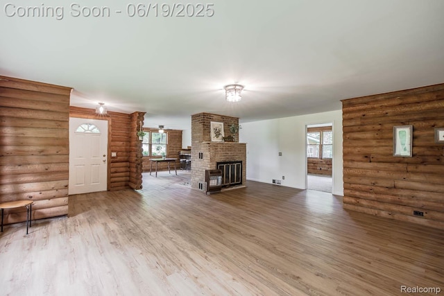 5180 Hillsboro Rd, Davisburg, MI 48350 - unfurnished living room featuring rustic walls, wood finished floors, plenty of natural light, and a brick fireplace