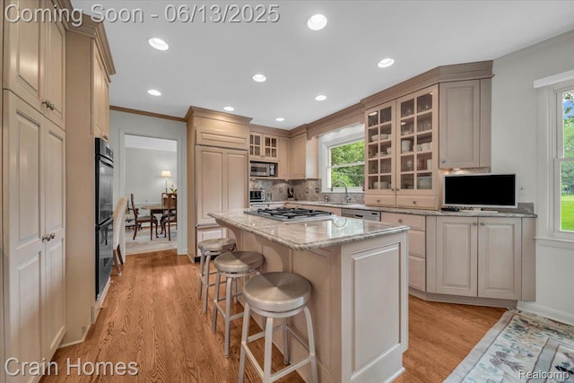 2861 Whittier Dr, Bloomfield Hills, MI 48304 - kitchen featuring appliances with stainless steel finishes, a kitchen island, light wood-style flooring, healthy amount of natural light, and ornamental molding