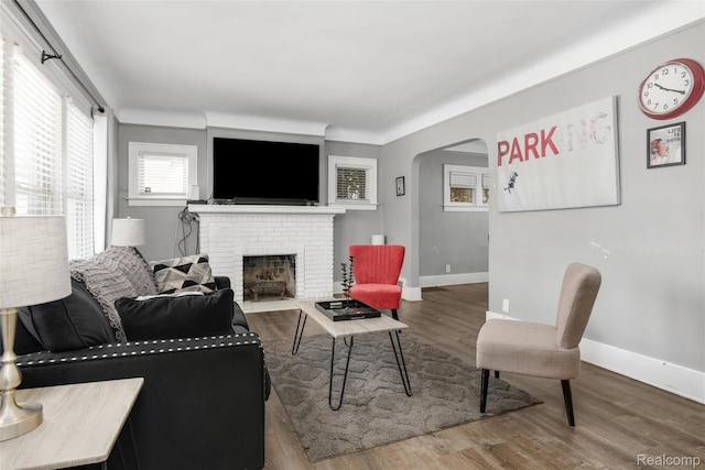 13572 Indiana St, Detroit, MI 48238 - living room featuring arched walkways, a brick fireplace, wood finished floors, and baseboards