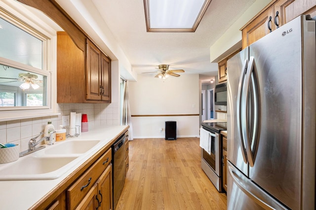 4292 Ashlawn Dr, Flint, MI 48507 - kitchen featuring appliances with stainless steel finishes, ceiling fan, brown cabinetry, and tasteful backsplash