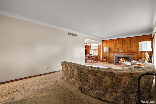 2652 Buckingham Ave, Berkley, MI 48072 - carpeted living room with baseboards, a fireplace with flush hearth, wood walls, and arched walkways
