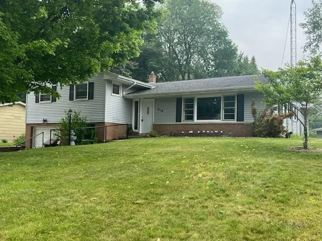 518 Hill Rd, Marshall, MI 49068 - split level home with a front lawn, a chimney, brick siding, and an attached garage