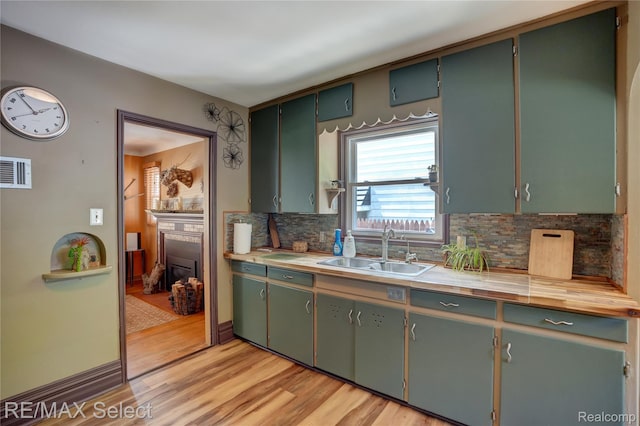 3418 Gratiot Ave, Flint, MI 48503 - kitchen with a fireplace with flush hearth, decorative backsplash, light wood finished floors, and light countertops
