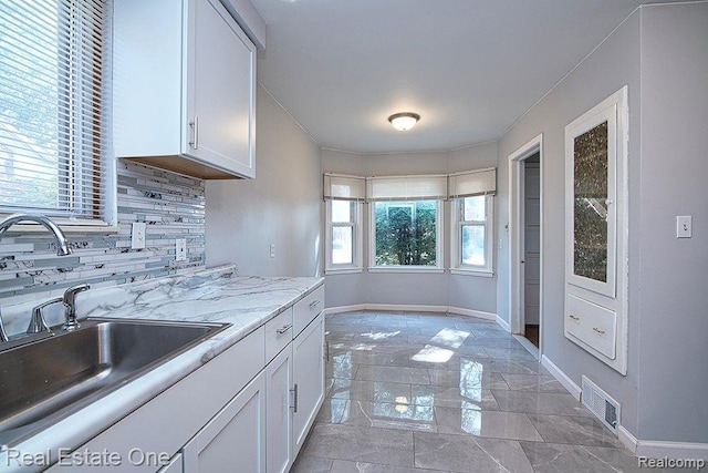 8035 Pinehurst St, Detroit, MI 48204 - kitchen featuring white cabinets, light marble finish floors, and backsplash