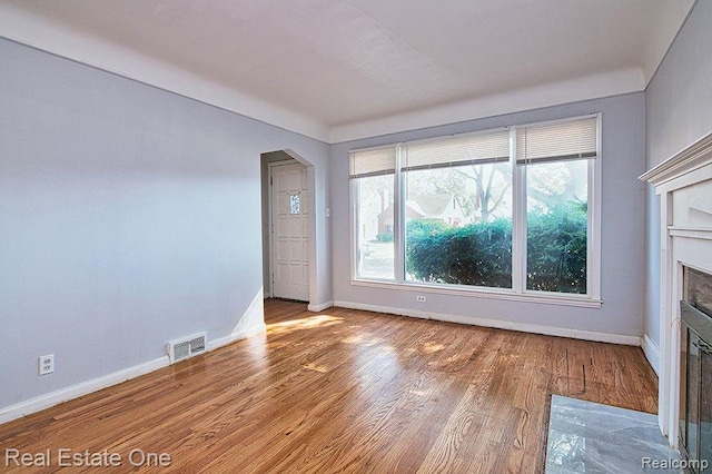 8035 Pinehurst St, Detroit, MI 48204 - unfurnished living room with wood finished floors, a fireplace with flush hearth, and arched walkways