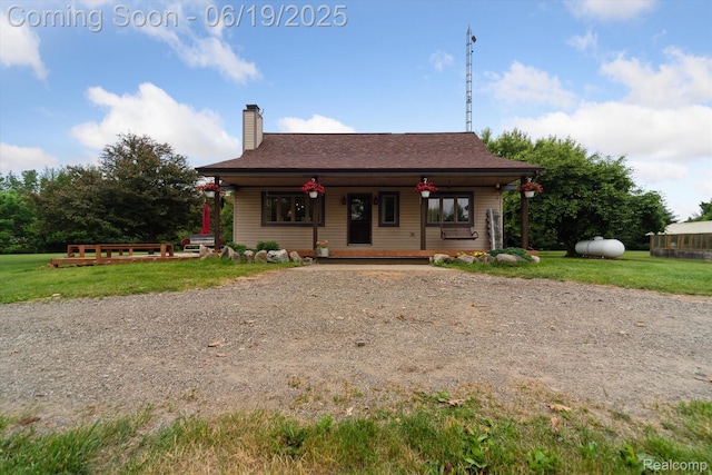 9808 Crofoot Rd, Fowlerville, MI 48836 - view of front of house featuring a chimney, a porch, a front yard, dirt driveway, and a shingled roof