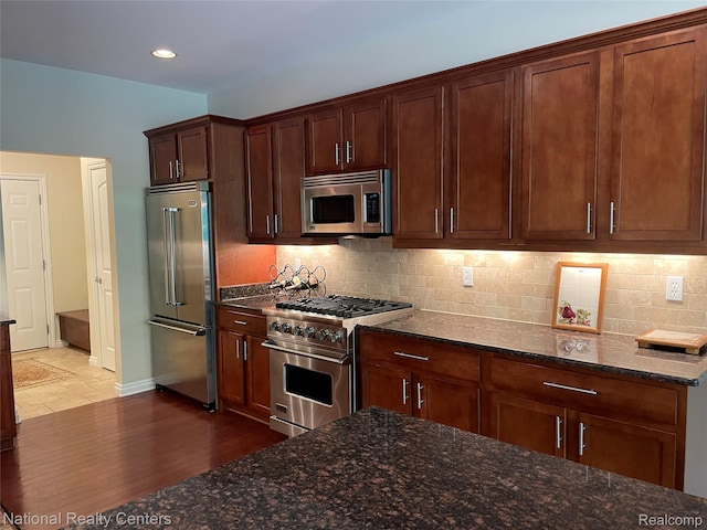 2750 Castlemartin Ct, Oakland, MI 48306 - kitchen with high quality appliances, dark stone counters, tasteful backsplash, dark wood-style flooring, and baseboards