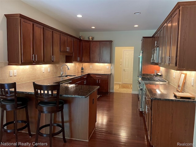 2750 Castlemartin Ct, Oakland, MI 48306 - kitchen featuring a sink, a peninsula, decorative backsplash, dark wood-style flooring, and stainless steel microwave
