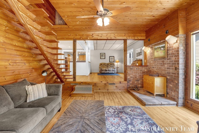 7120 Quarterline Rd, Spring Lake, MI 49456 - living room with wood finished floors, wood walls, a ceiling fan, stairs, and brick wall