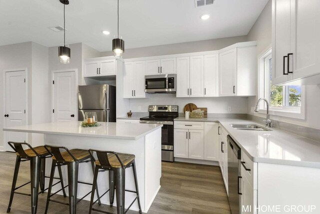 13654 Signature Dr, Holland, MI 49424 - kitchen featuring stainless steel appliances, a sink, dark wood-type flooring, a kitchen breakfast bar, and recessed lighting