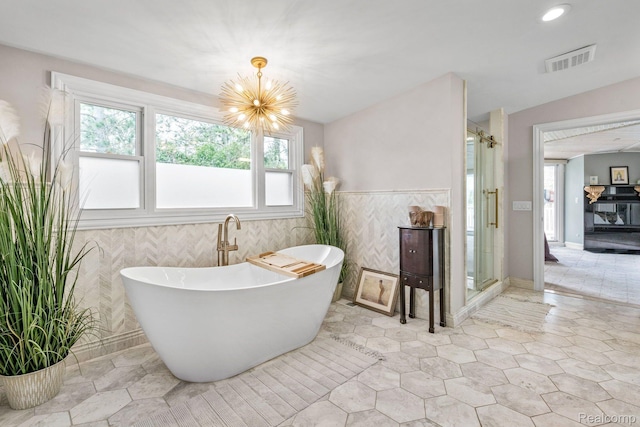 900 Indianwood Rd, Lake Orion, MI 48362 - bathroom with a soaking tub, a chandelier, healthy amount of natural light, a stall shower, and tile walls