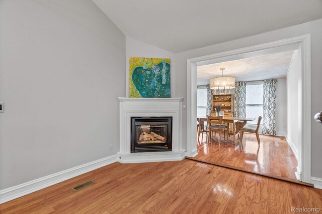 900 Indianwood Rd, Lake Orion, MI 48362 - living room featuring wood finished floors, vaulted ceiling, a glass covered fireplace, and baseboards