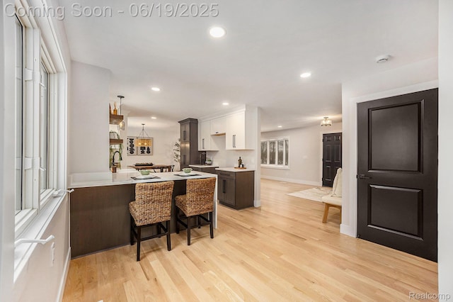 54232 Mound Rd, Shelby Twp, MI 48316 - kitchen with a breakfast bar area, light countertops, a peninsula, light wood finished floors, and recessed lighting