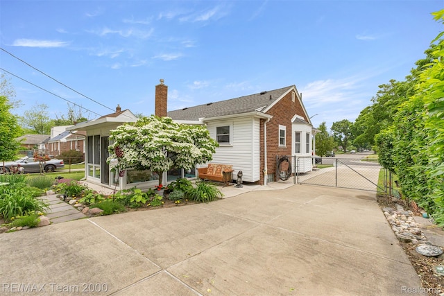 18155 Audette St, Dearborn, MI 48124 - back of property with a gate, brick siding, a sunroom, a chimney, and a shingled roof