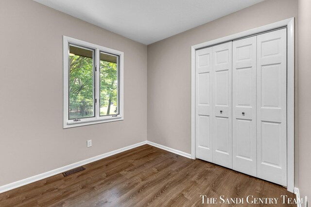 6372 Lake Harbor Rd, Norton Shores, MI 49441 - unfurnished bedroom with baseboards, wood finished floors, and a closet