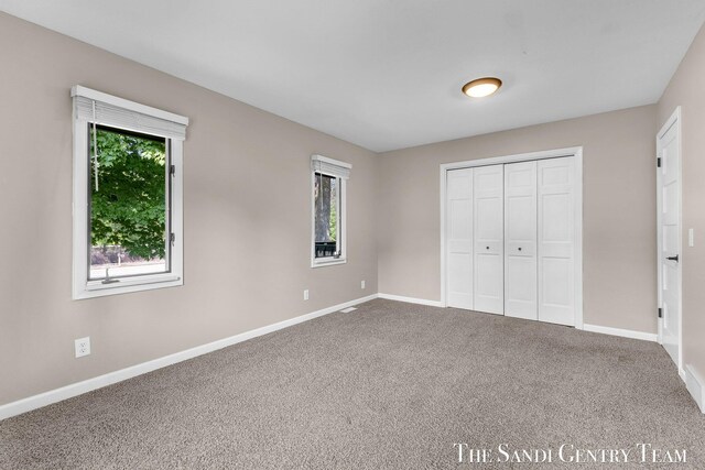 6372 Lake Harbor Rd, Norton Shores, MI 49441 - unfurnished bedroom featuring baseboards, carpet floors, and a closet