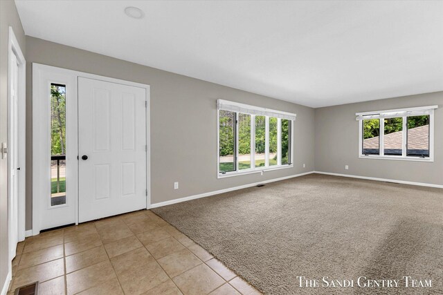 6372 Lake Harbor Rd, Norton Shores, MI 49441 - foyer with light carpet, baseboards, and light tile patterned floors