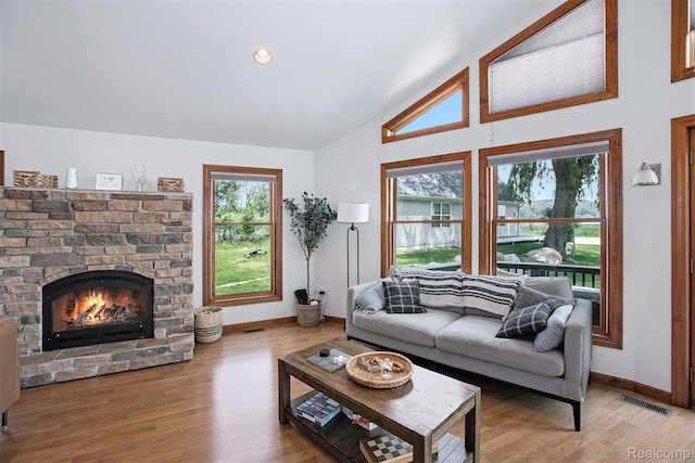 8721 Bayview Rd, Onekama, MI 49675 - living area featuring a warm lit fireplace, vaulted ceiling, and wood finished floors