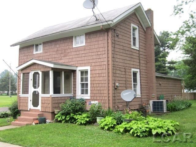 311 Tiffin St, Hudson, MI 49247 - view of front of home featuring central air condition unit, a chimney, entry steps, and a front lawn