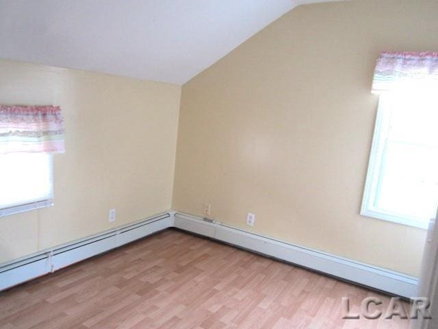 311 Tiffin St, Hudson, MI 49247 - unfurnished room featuring healthy amount of natural light, lofted ceiling, light wood-style flooring, and a baseboard radiator