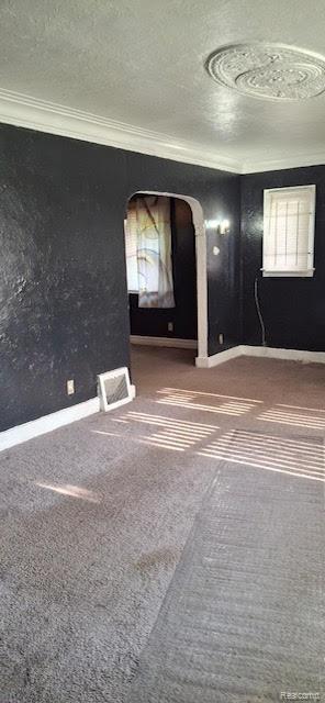 15859 Braile St, Detroit, MI 48223 - unfurnished room featuring carpet floors, a textured ceiling, crown molding, baseboards, and arched walkways