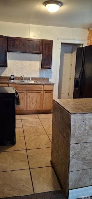 15859 Braile St, Detroit, MI 48223 - kitchen featuring black fridge with ice dispenser, light tile patterned flooring, tasteful backsplash, a sink, and dark brown cabinets