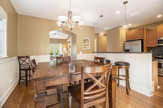 23 Kenneth St, Pentwater, MI 49449 - dining space with arched walkways, light wood-style floors, wainscoting, a chandelier, and recessed lighting