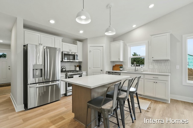 345 Hickory Valley Dr, Kalamazoo, MI 49009 - kitchen with stainless steel appliances, backsplash, white cabinetry, a center island, and light wood-type flooring