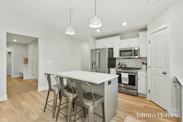 345 Hickory Valley Dr, Kalamazoo, MI 49009 - kitchen with stainless steel appliances, decorative backsplash, a kitchen bar, a kitchen island, and white cabinetry