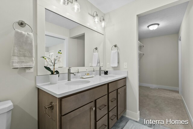 345 Hickory Valley Dr, Kalamazoo, MI 49009 - bathroom with double vanity, toilet, and baseboards