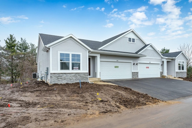 345 Hickory Valley Dr, Kalamazoo, MI 49009 - view of front of house featuring stone siding, asphalt driveway, central air condition unit, an attached garage, and board and batten siding