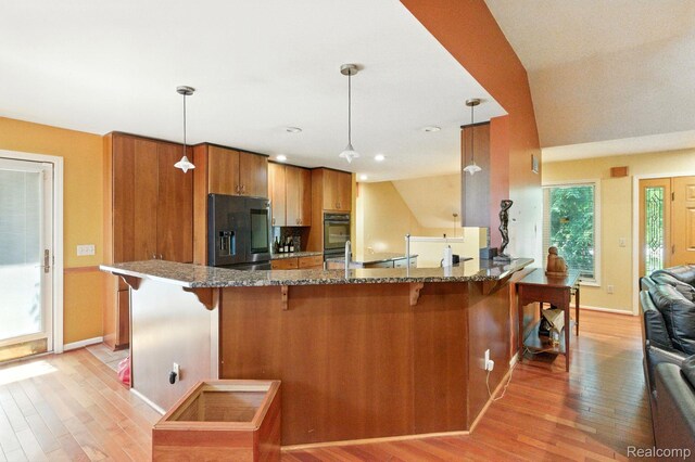 3680 Miller Rd, Ann Arbor, MI 48103 - kitchen featuring refrigerator with ice dispenser, brown cabinetry, light wood-style flooring, a kitchen breakfast bar, and a peninsula