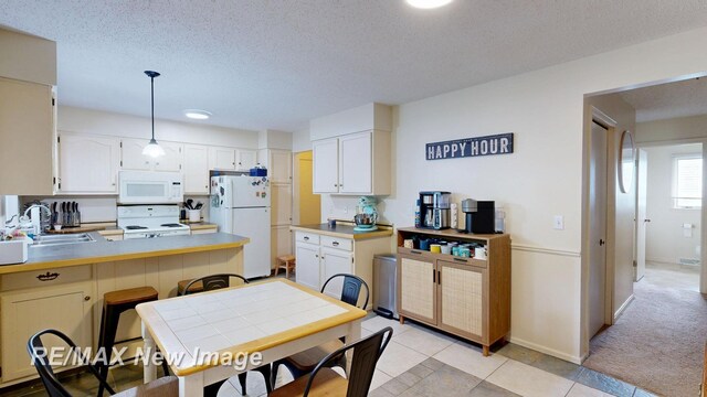 3257 N Christy Way, Saginaw, MI 48603 - kitchen featuring white appliances, a sink, a textured ceiling, a peninsula, and decorative light fixtures