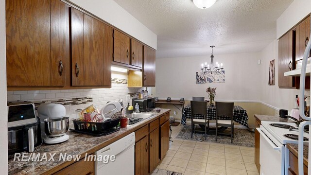 3257 N Christy Way, Saginaw, MI 48603 - kitchen featuring white appliances, a chandelier, light tile patterned floors, decorative backsplash, and brown cabinets