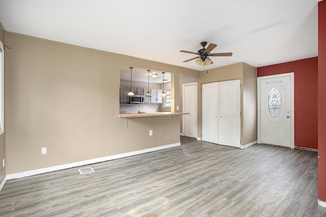 1767 W Michigan Ave, Battle Creek, MI 49037 - unfurnished living room featuring ceiling fan, wood finished floors, and baseboards