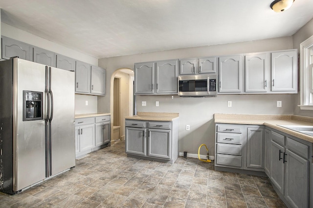 1767 W Michigan Ave, Battle Creek, MI 49037 - kitchen with stainless steel appliances, gray cabinetry, arched walkways, and stone finish flooring