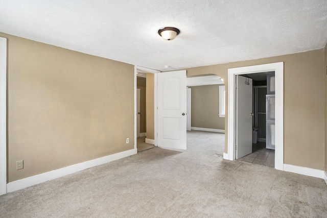 1767 W Michigan Ave, Battle Creek, MI 49037 - unfurnished bedroom with arched walkways, light colored carpet, a textured ceiling, and baseboards