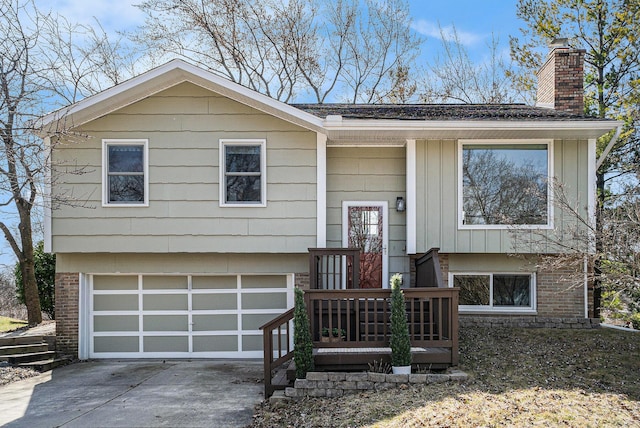 2149 Fair St, Ann Arbor, MI 48103 - split foyer home featuring a chimney, an attached garage, driveway, board and batten siding, and brick siding