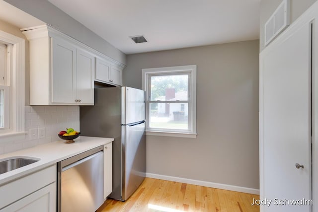 6449 Wendell St SE, Grand Rapids, MI 49546 - kitchen featuring stainless steel appliances, light wood-style flooring, white cabinets, and light countertops