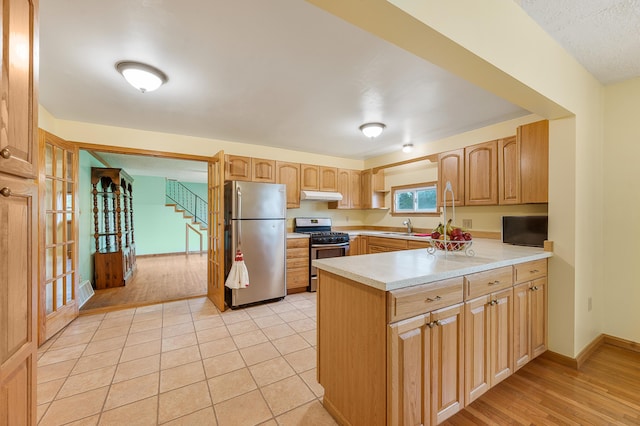 20550 19 Mile Rd, Big Rapids, MI 49307 - kitchen with stainless steel appliances, a peninsula, under cabinet range hood, a sink, and light countertops