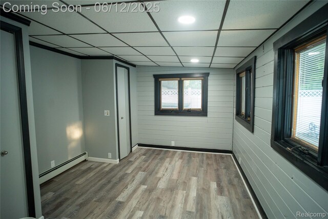 626 Wilwood Rd, Rochester Hills, MI 48309 - unfurnished room featuring a baseboard heating unit, a drop ceiling, wood finished floors, and baseboards