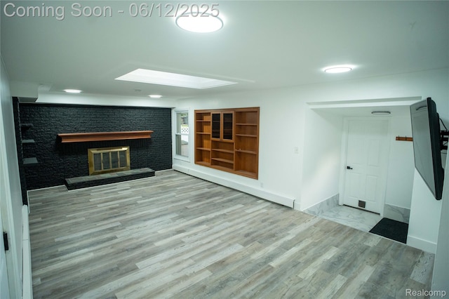626 Wilwood Rd, Rochester Hills, MI 48309 - unfurnished living room featuring a brick fireplace, wood finished floors, a skylight, and baseboards