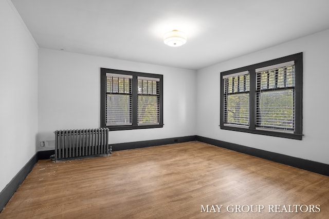 1951 Leonard St NW, Grand Rapids, MI 49504 - spare room with radiator heating unit, plenty of natural light, wood finished floors, and baseboards