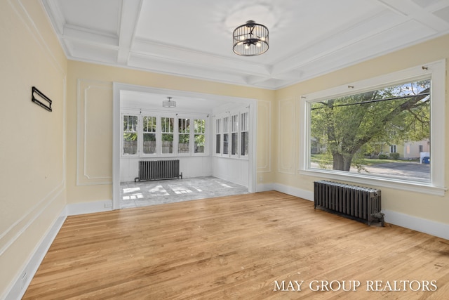1951 Leonard St NW, Grand Rapids, MI 49504 - unfurnished living room with radiator, coffered ceiling, beam ceiling, wood finished floors, and a chandelier