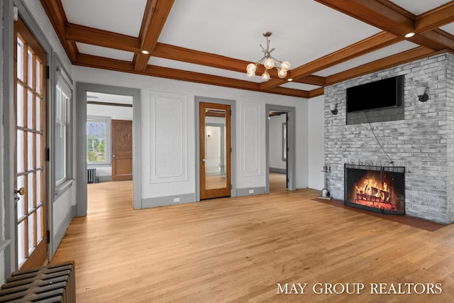 1951 Leonard St NW, Grand Rapids, MI 49504 - unfurnished living room with coffered ceiling, light wood-style floors, beam ceiling, a brick fireplace, and a chandelier