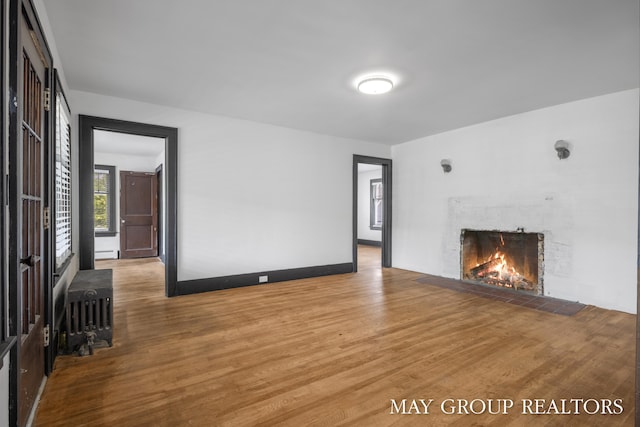 1951 Leonard St NW, Grand Rapids, MI 49504 - unfurnished living room featuring a fireplace, wood finished floors, radiator, and baseboard heating