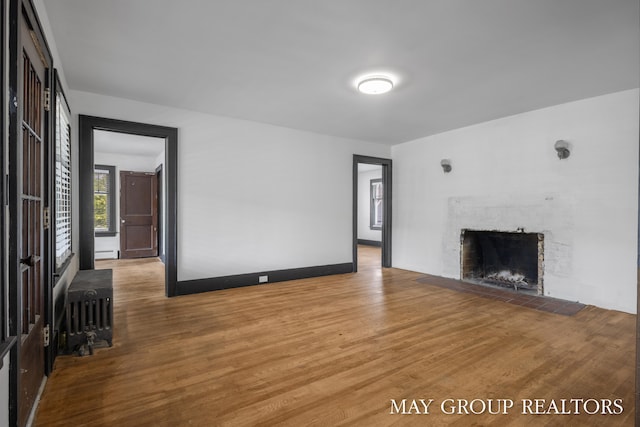 1951 Leonard St NW, Grand Rapids, MI 49504 - unfurnished living room featuring a fireplace, wood finished floors, radiator heating unit, and baseboard heating